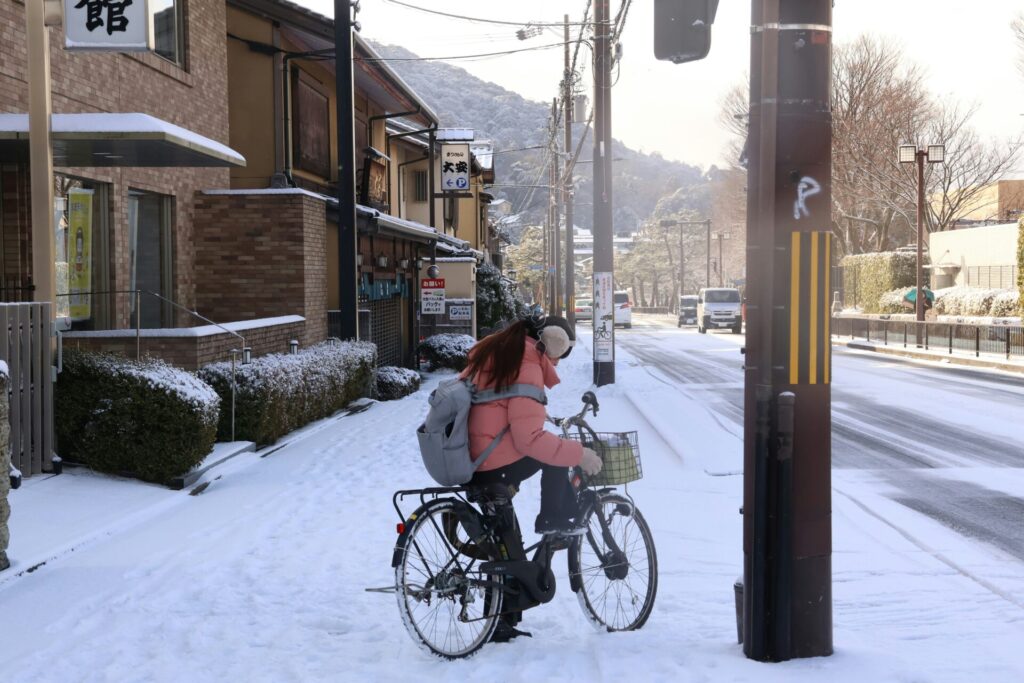イヤーマフをして、雪道で自転車に乗る女性