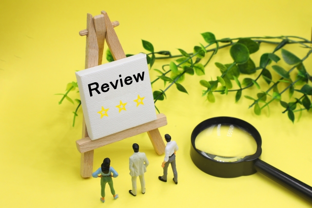 虫眼鏡とReviewの文字を見ている人たち