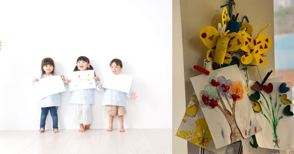 画用紙をもっている3人の子供たちと壁に飾られている作品