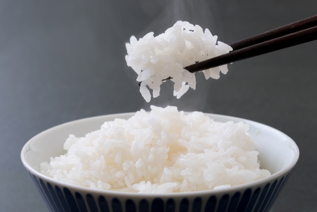 お茶碗に持ったご飯を箸でつかんでいる様子